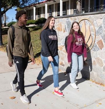 Three students walking together on the quad in fall